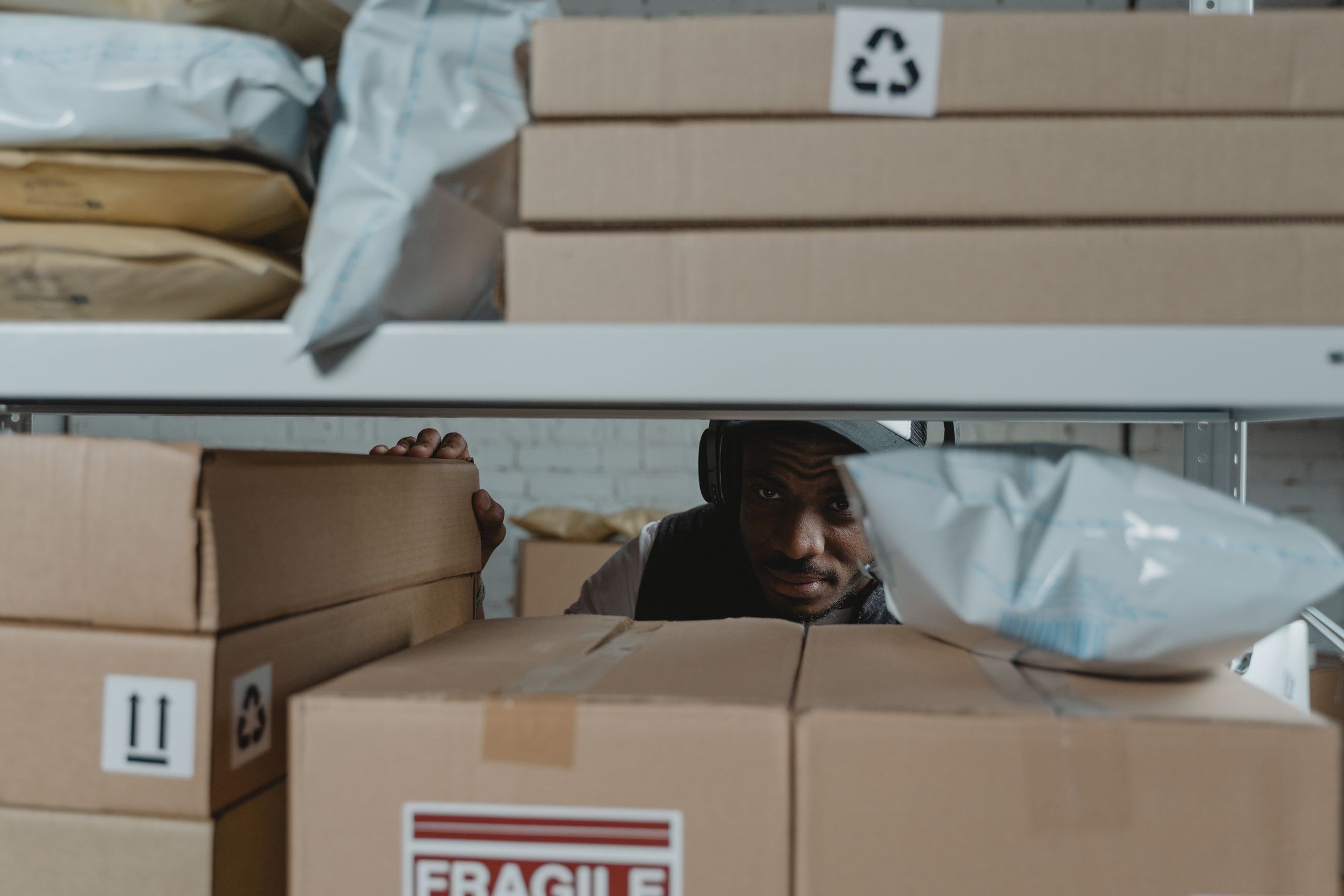 Warehouse worker inspecting cardboard parcels on storage shelves